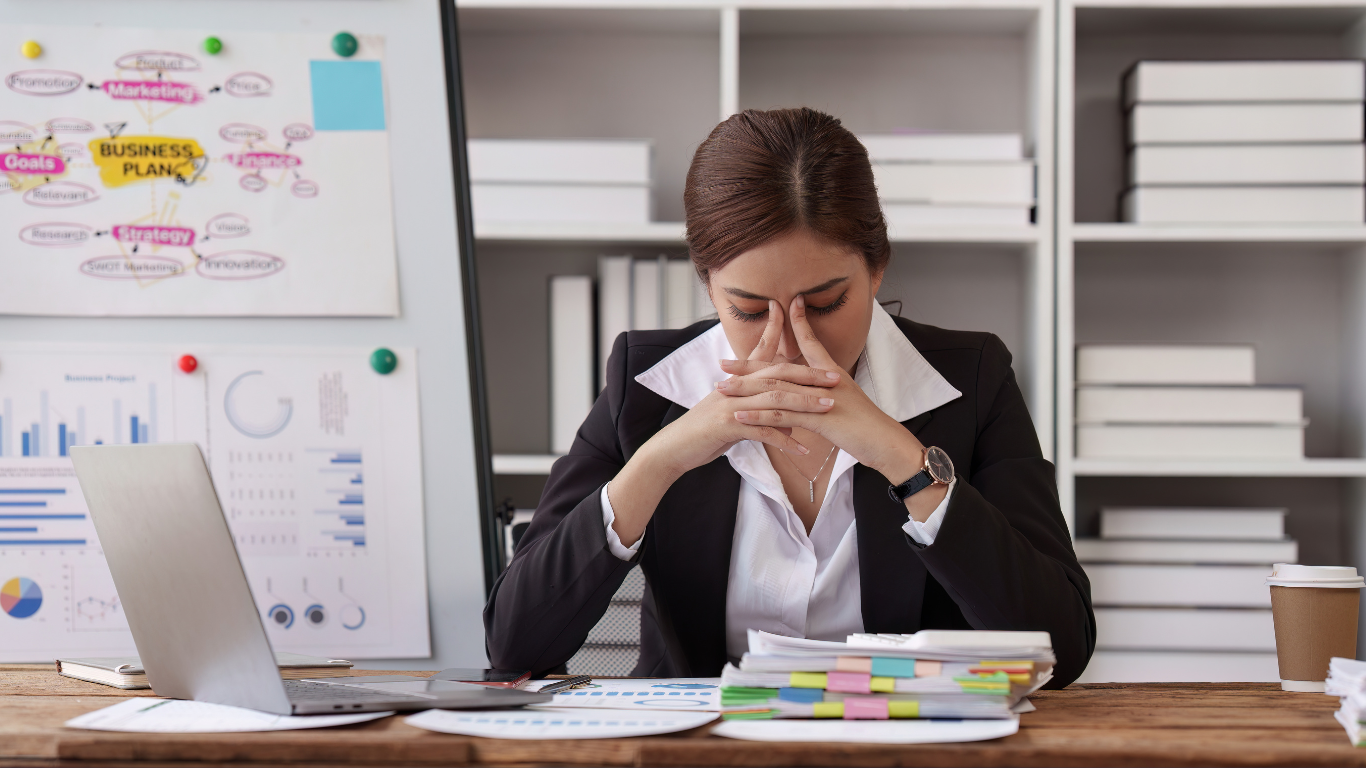 a lady sitting at a desk with her head in her hands